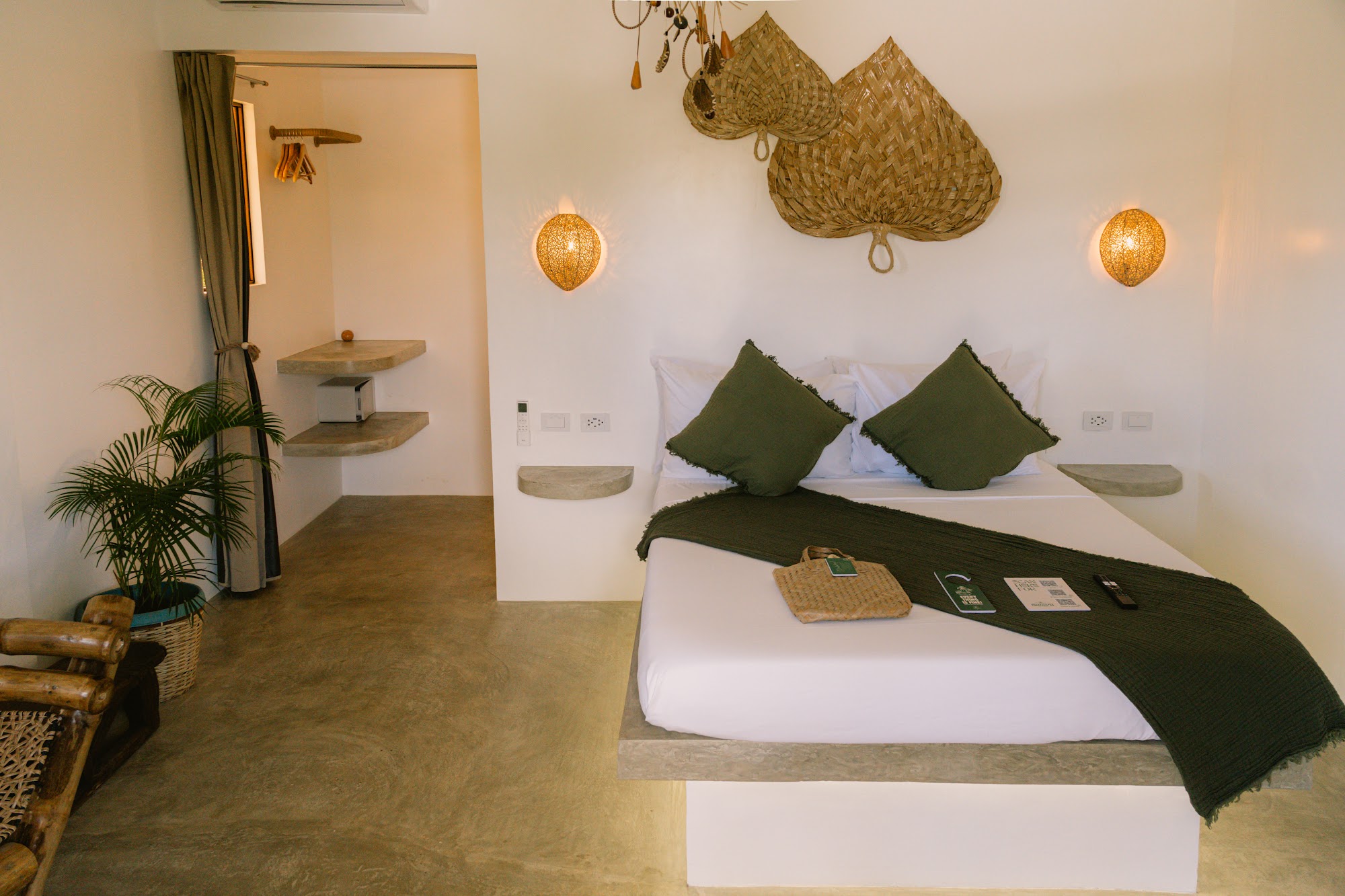 Deluxe Balcony room with queen bed, green cushions and natural woven finishes